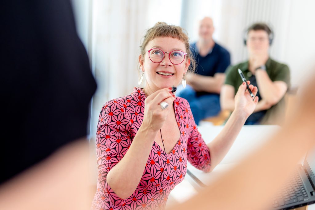 Inga spricht in ein Handmikro. In der Hand hält sie einen Kuli.